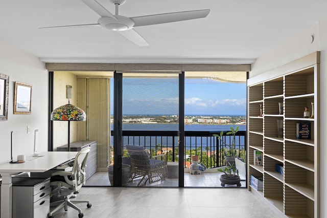 office area featuring ceiling fan, a wall of windows, and a water view