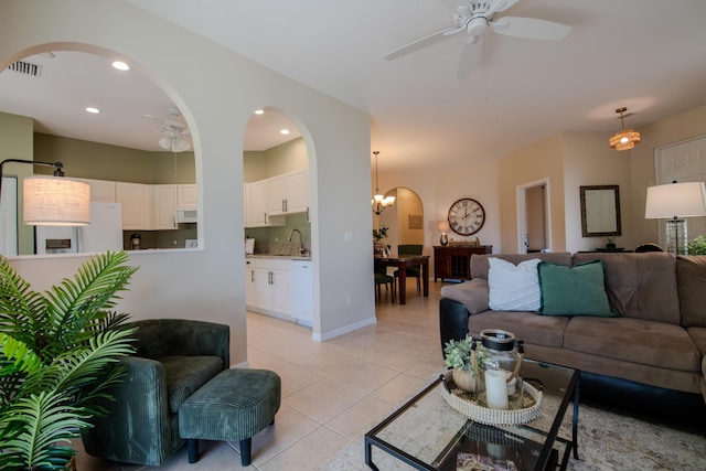 living room featuring ceiling fan with notable chandelier, sink, and light tile patterned floors