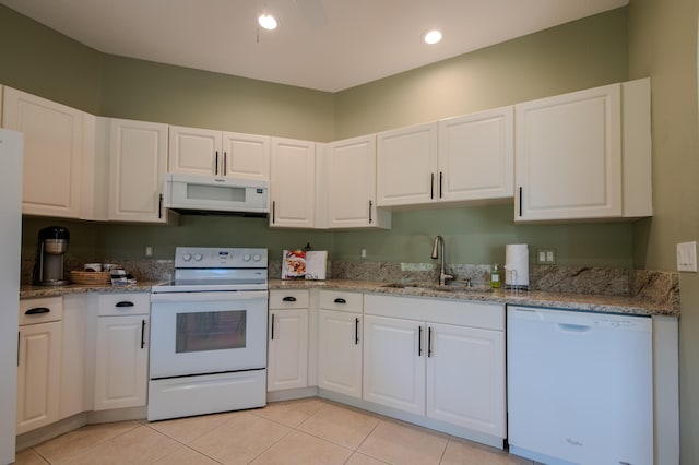 kitchen with light tile patterned flooring, white cabinetry, sink, light stone countertops, and white appliances