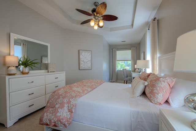 bedroom with a raised ceiling, ceiling fan, and light tile patterned flooring