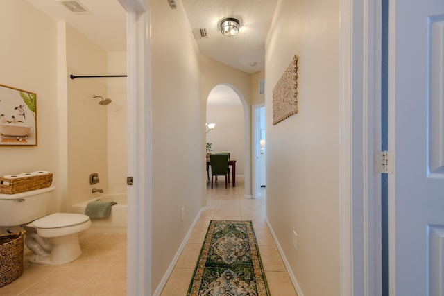 hallway with light tile patterned floors and a textured ceiling