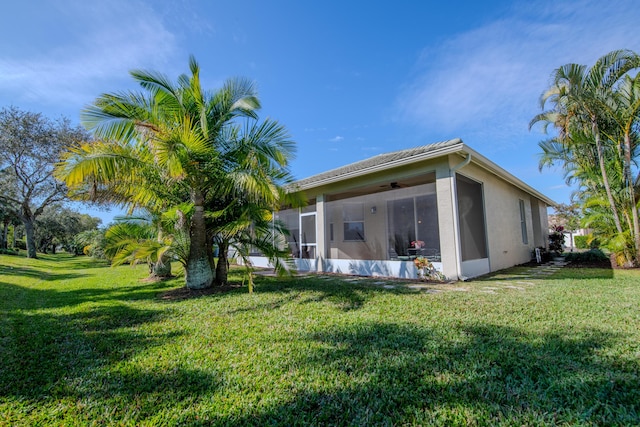 back of property with a sunroom, a yard, and ceiling fan