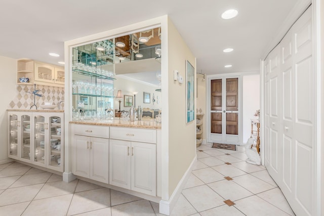 bar featuring decorative backsplash, light tile patterned flooring, white cabinetry, and light stone counters