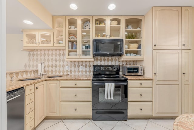 kitchen with light stone countertops, black appliances, tasteful backsplash, light tile patterned flooring, and sink