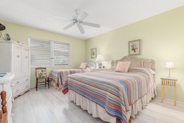 bedroom with ceiling fan, light hardwood / wood-style flooring, and a textured ceiling