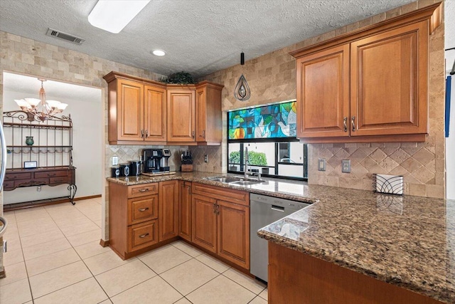 kitchen with dark stone counters, sink, stainless steel dishwasher, light tile patterned floors, and a notable chandelier