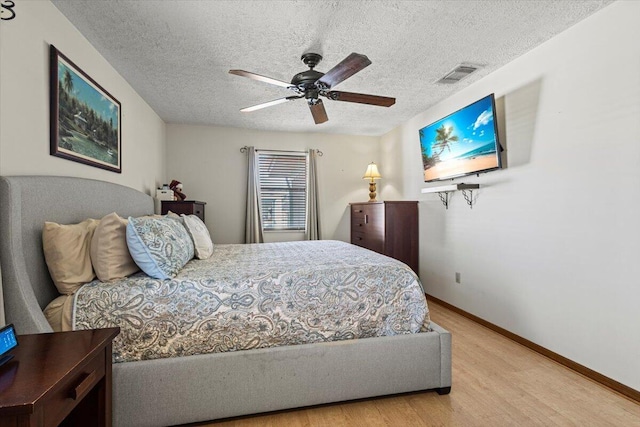 bedroom with ceiling fan, light hardwood / wood-style floors, and a textured ceiling