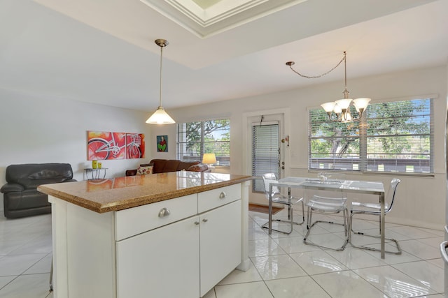 kitchen with white cabinets, a raised ceiling, a chandelier, and hanging light fixtures