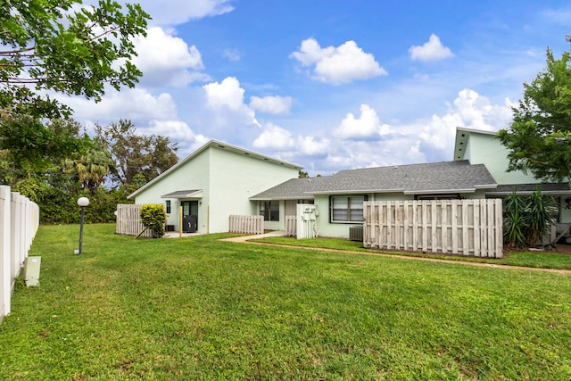 back of property with a yard and central AC unit