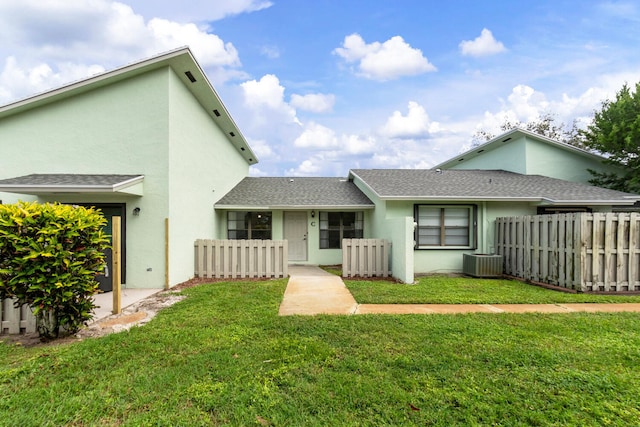 back of property with a yard and central AC