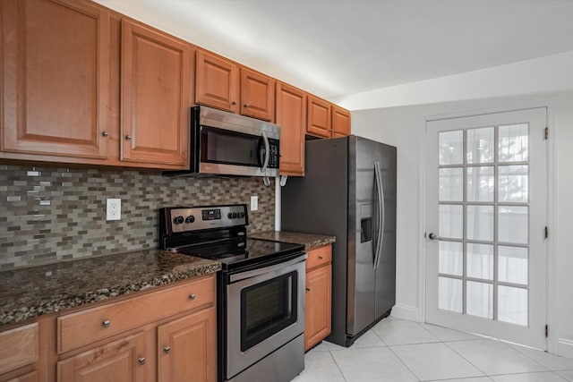 kitchen featuring stainless steel appliances, light tile patterned flooring, dark stone countertops, and tasteful backsplash