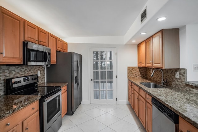 kitchen with sink, stainless steel appliances, dark stone counters, and backsplash