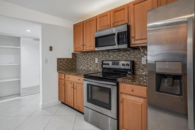 kitchen featuring stainless steel appliances, backsplash, light tile patterned floors, and dark stone counters