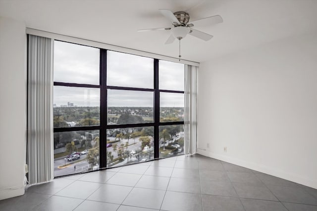 tiled spare room featuring floor to ceiling windows and ceiling fan