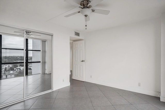 tiled empty room featuring ceiling fan