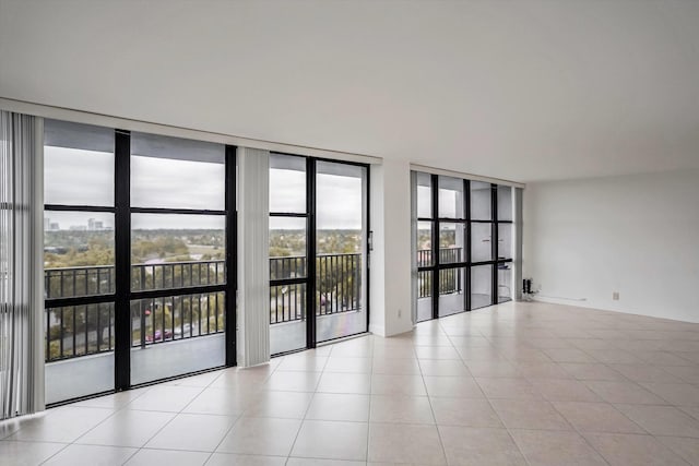 spare room with light tile patterned flooring and a wall of windows