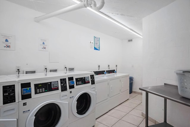 laundry room with washing machine and clothes dryer and light tile patterned floors