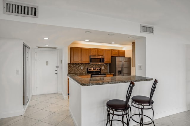 kitchen with kitchen peninsula, stainless steel appliances, dark stone counters, and backsplash