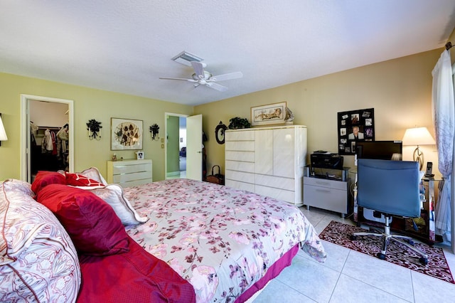 tiled bedroom with a textured ceiling, ceiling fan, a spacious closet, and a closet