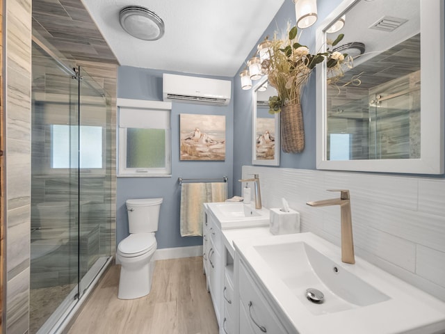 bathroom with a wall mounted AC, wood-type flooring, toilet, a shower with door, and vanity