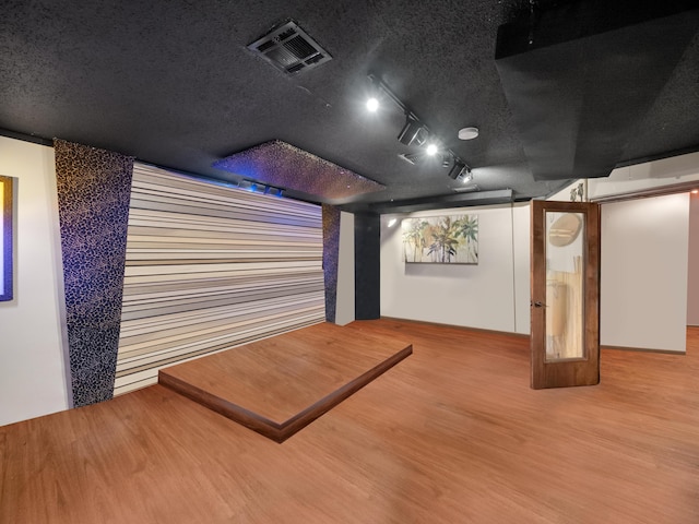 cinema room with hardwood / wood-style flooring and track lighting