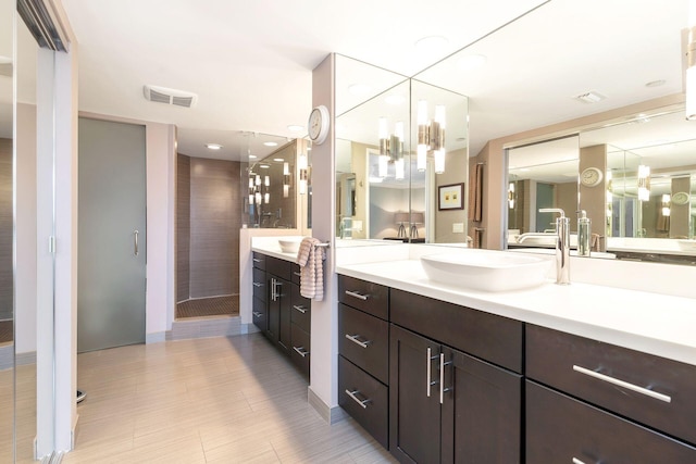 bathroom with tiled shower, vanity, and a notable chandelier