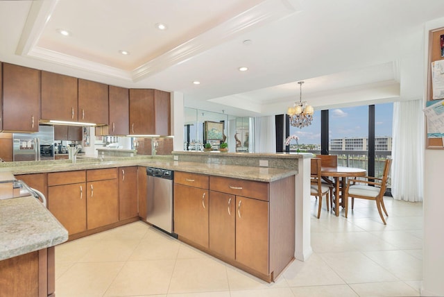 kitchen featuring pendant lighting, stainless steel dishwasher, kitchen peninsula, a raised ceiling, and an inviting chandelier