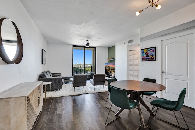 dining space featuring a textured ceiling, ceiling fan, a wall of windows, and dark wood-type flooring