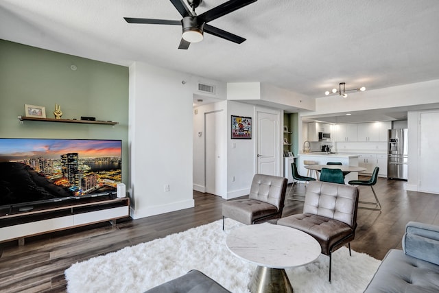 living room with ceiling fan, dark hardwood / wood-style flooring, and a textured ceiling