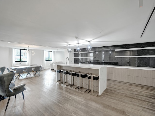 kitchen featuring a large island, a kitchen breakfast bar, decorative light fixtures, and light hardwood / wood-style flooring