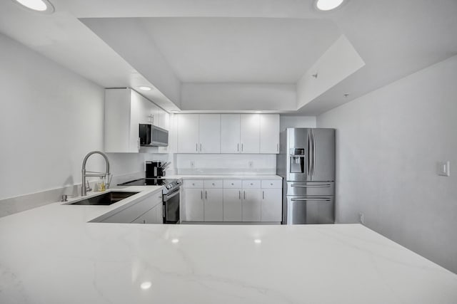 kitchen featuring kitchen peninsula, stainless steel appliances, a raised ceiling, sink, and white cabinets