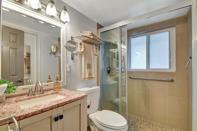 bathroom featuring toilet, a shower with shower door, and vanity