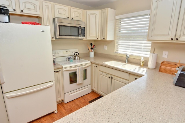 kitchen with white appliances, light wood-type flooring, and sink