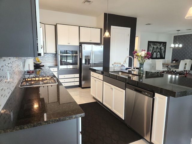 kitchen with sink, white cabinetry, stainless steel appliances, a center island, and decorative light fixtures