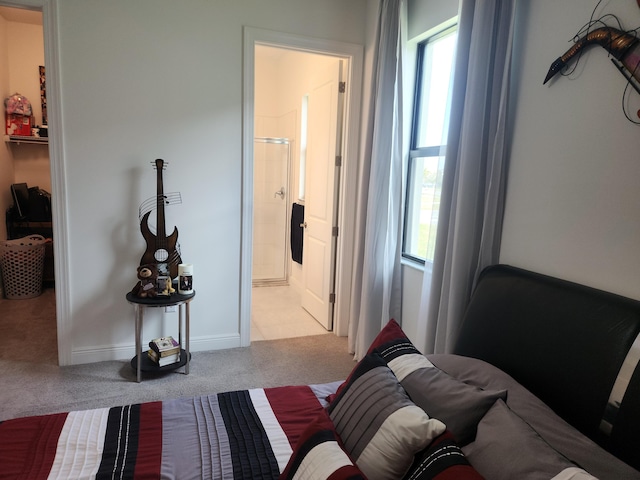 carpeted bedroom featuring baseboards and ensuite bath