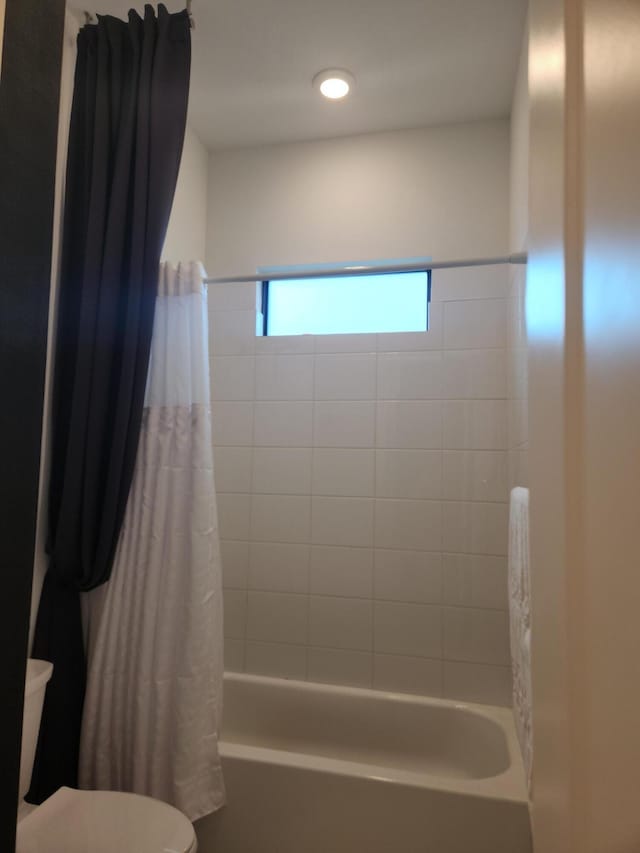 full bath featuring toilet and shower / bath combo with shower curtain