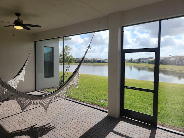 unfurnished sunroom featuring a ceiling fan and a water view