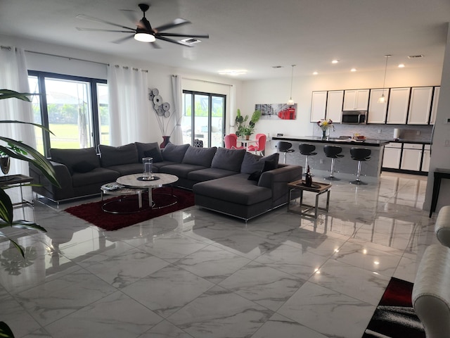 living area featuring recessed lighting, marble finish floor, and a ceiling fan