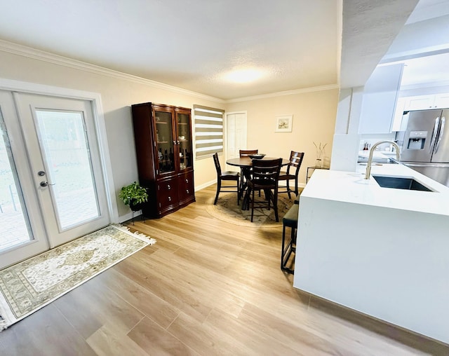 kitchen featuring sink, crown molding, white cabinetry, stainless steel fridge with ice dispenser, and light wood-type flooring