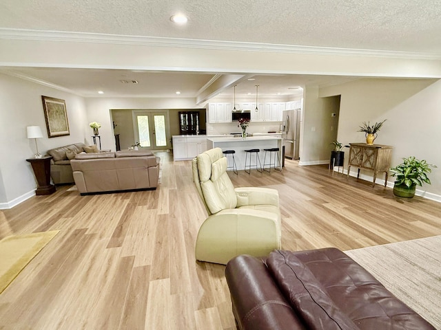 living room featuring french doors, ornamental molding, a textured ceiling, and light wood-type flooring