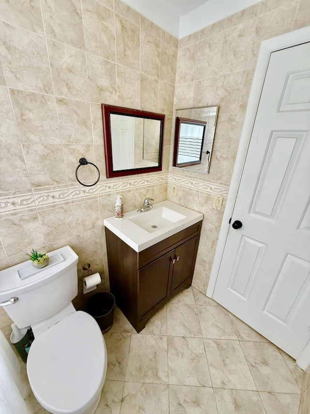 bathroom with vanity, toilet, and tile walls