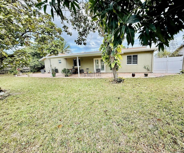 back of house with a patio area and a lawn