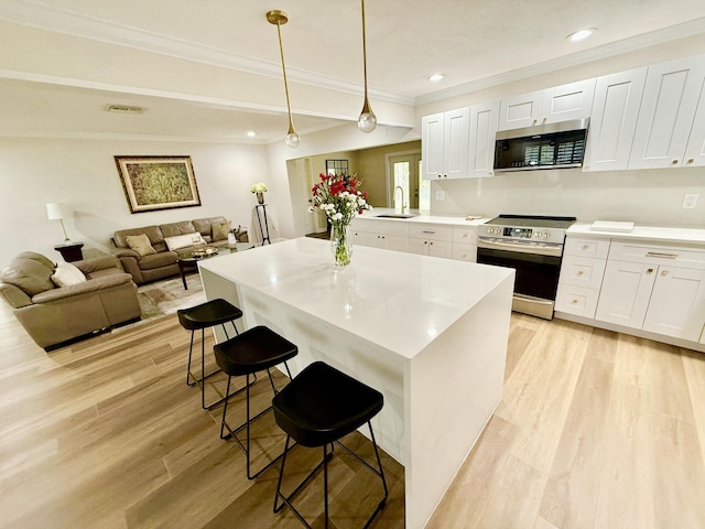 kitchen featuring white cabinetry, sink, a breakfast bar area, hanging light fixtures, and stainless steel appliances