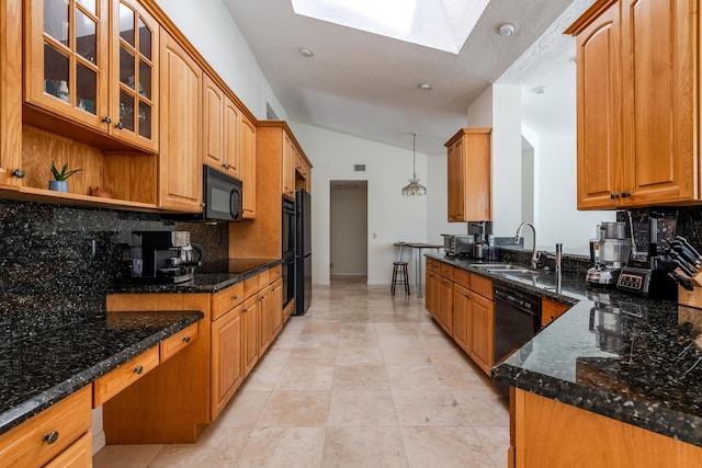 kitchen with black appliances, sink, vaulted ceiling with skylight, dark stone countertops, and decorative light fixtures