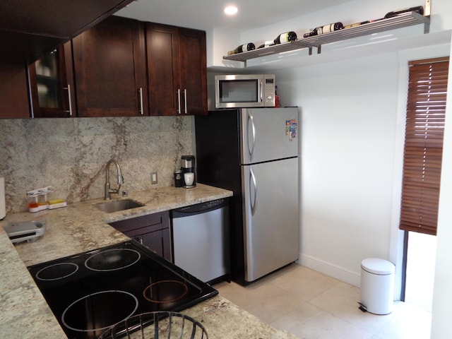 kitchen with sink, stainless steel appliances, tasteful backsplash, light stone counters, and light tile patterned floors