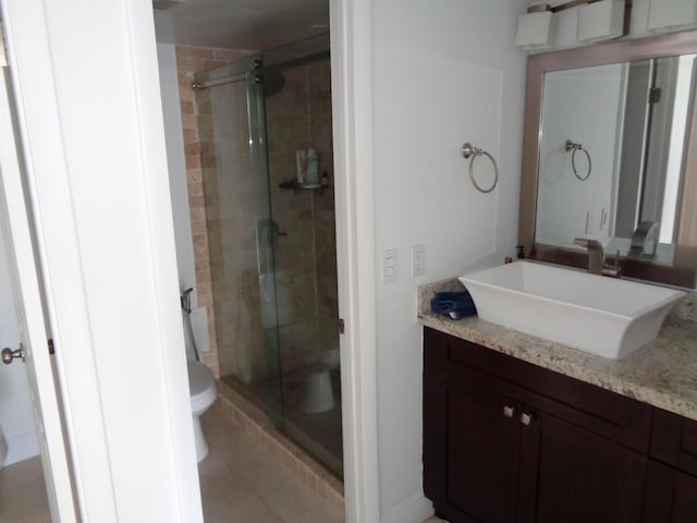 bathroom with tile patterned flooring, vanity, toilet, and a shower with shower door