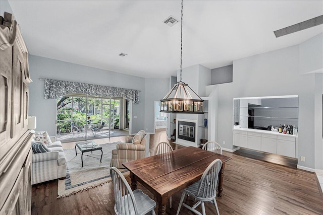 dining area featuring dark wood-type flooring and an inviting chandelier