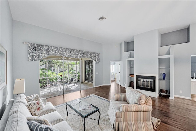 living room with hardwood / wood-style floors, built in shelves, and a high ceiling