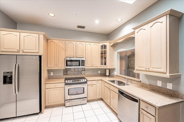 kitchen with sink, light tile patterned floors, light brown cabinets, and appliances with stainless steel finishes