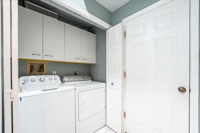 clothes washing area featuring cabinets, light tile patterned floors, and washing machine and dryer